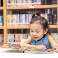 kleines Mädchen liest ein Kinderbuch in der Bibliothek