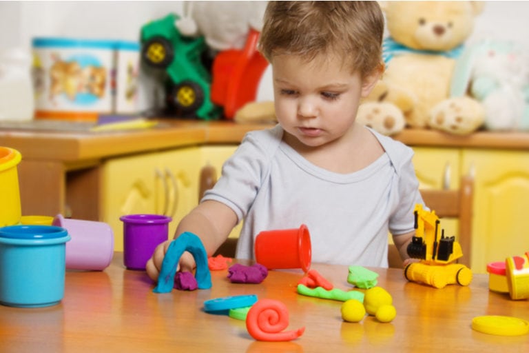 Zweijähriges Kind spielt mit Spielzeug im Kinderzimmer