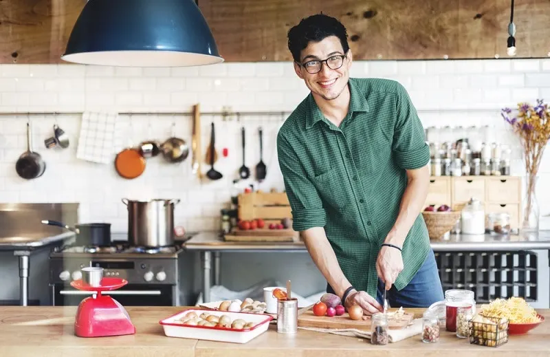 gut aussehender junger Mann mit Brille kocht in der Küche