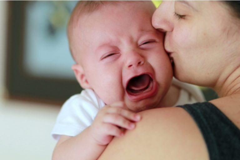 Mutter hält und beruhigt ihr weinendes Baby, das nicht trinken will