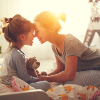 Mutter weckt morgens ihre Tochter im Bett