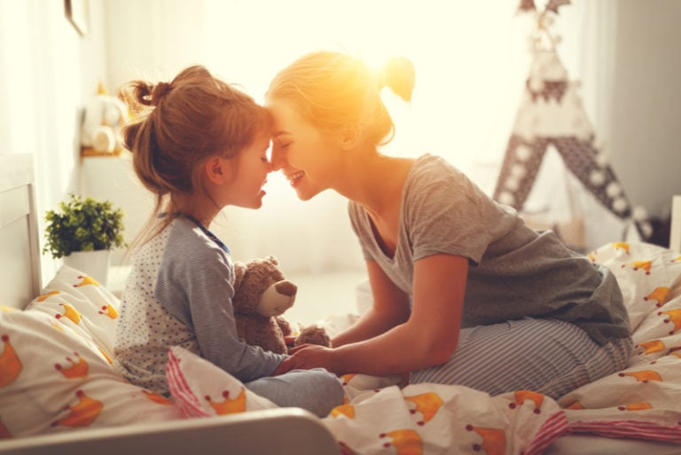 Mutter weckt morgens ihre Tochter im Bett