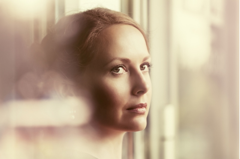 Traurige schöne Frau, die aus dem Fenster schaut