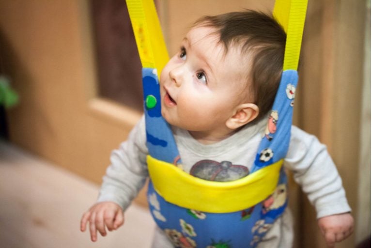 kleines Baby sitzt in einem Türhopser und schaut nach oben