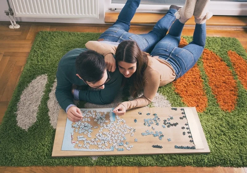 ein Paar macht ein Puzzle auf dem Boden des Wohnzimmers