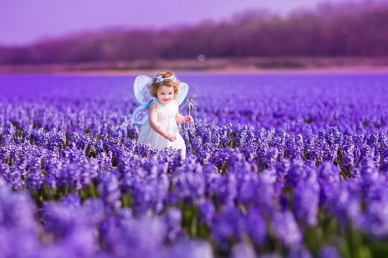 kleines Mädchen trägt ein schönes Kleid und geht in einem lila Blumenfeld