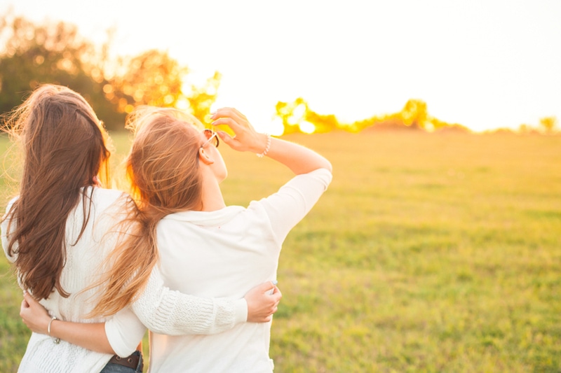 zwei Freundinnen umarmen und genießen den Sonnenuntergang