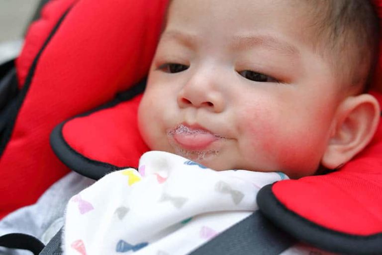 Kleines Baby spuckt beim Sitzen in einem Autositz