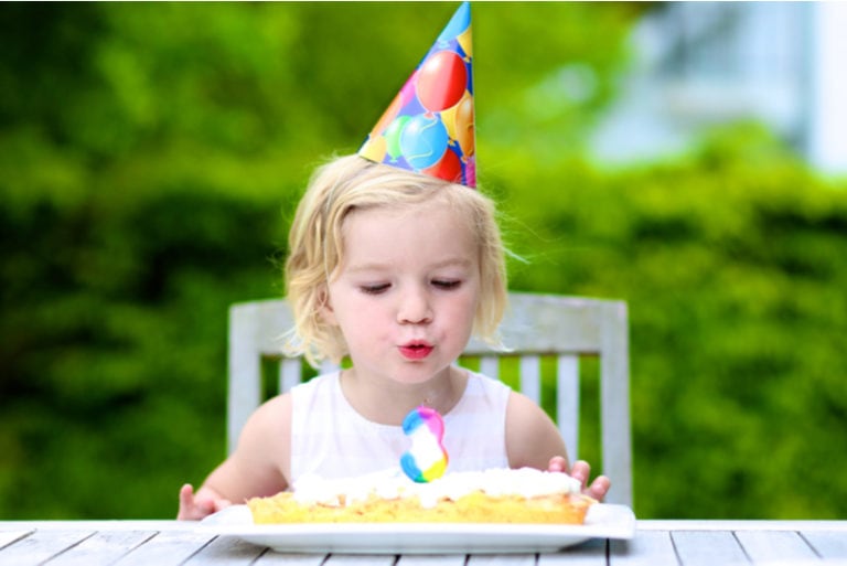 kleines Mädchen feiert ihren dritten Geburtstag mit einer Torte