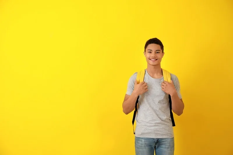 Jugendlicher mit Rucksack vor einem gelben Hintergrund
