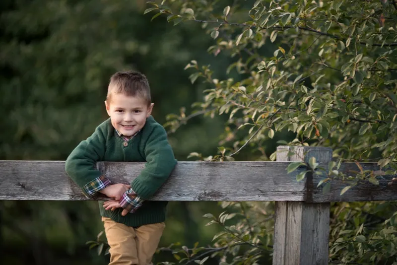 Kind im Park kletterte auf einen Holzzaun