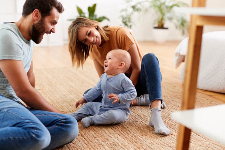 Eltern, die zu Hause auf dem Boden sitzen und mit Baby-Sohn spielen