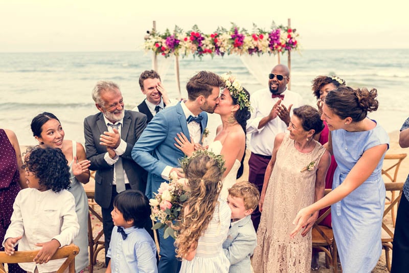 Paar küsst sich nach der Hochzeitszeremonie im Kreise der Gäste