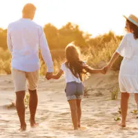 Mama und Papa machen einen Spaziergang mit ihrer Tochter am Strand