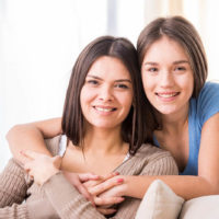 Schöne Mutter und ihre süße Tochter lächeln und posieren zu Hause