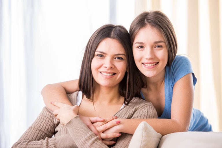 Schöne Mutter und ihre süße Tochter lächeln und posieren zu Hause