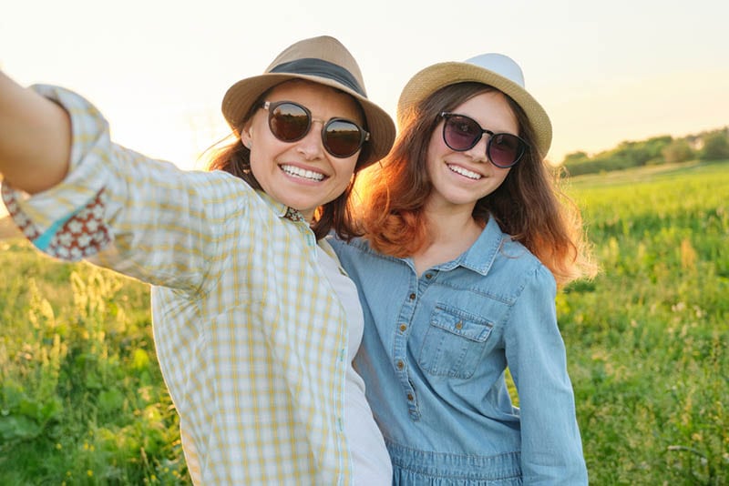 glückliche Frau und jugendliches Mädchen mit Sonnenbrille machen ein Selfie