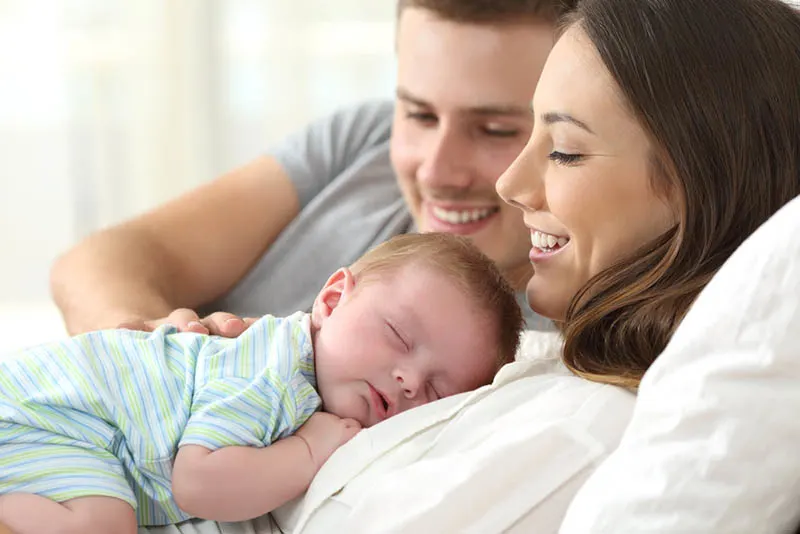 glückliche junge Eltern, die ihr Baby beim Schlafen beobachten