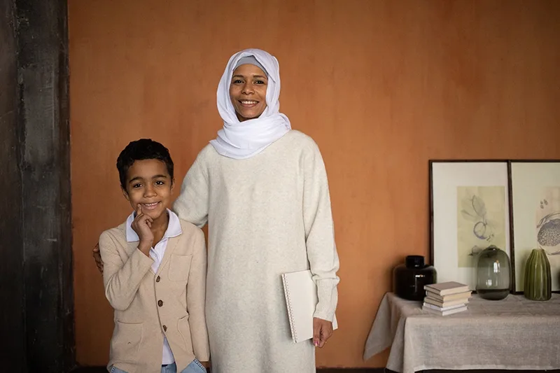 Arabische Mutter im Hijab mit glücklichem Sohn, der im Raum steht