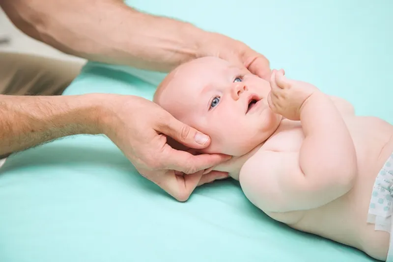 Arzt untersucht Baby und berührt ihren Kopf