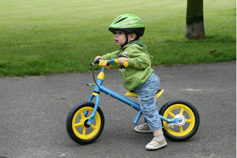 Baby Junge lernt auf einem ersten Fahrrad zu fahren