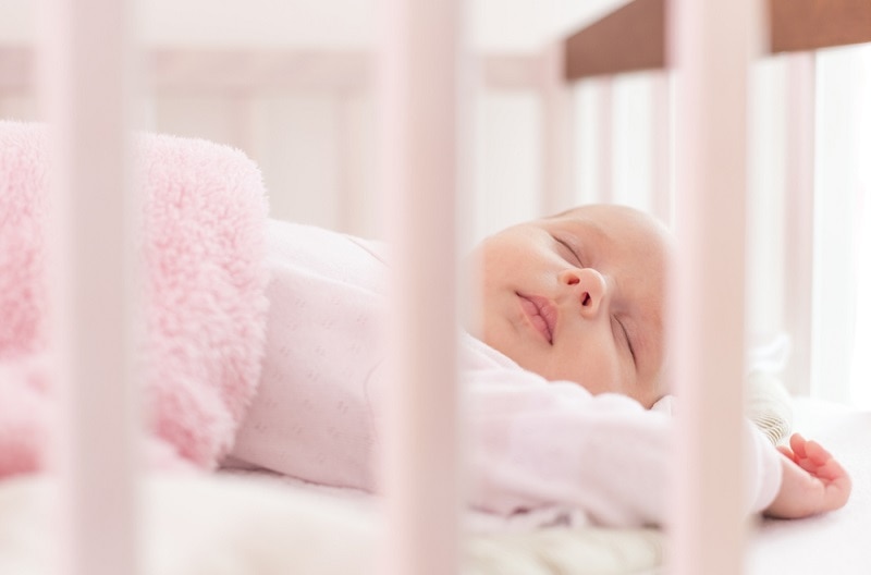 Das kleine Mädchen schläft in ihrem Bettchen