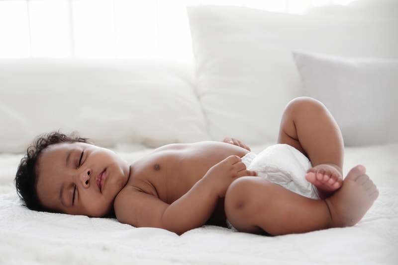 Baby schläft auf dem Rücken auf dem Bett