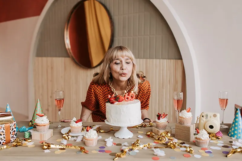 Frau bläst Kerzen auf den Kuchen zum 60. Geburtstag