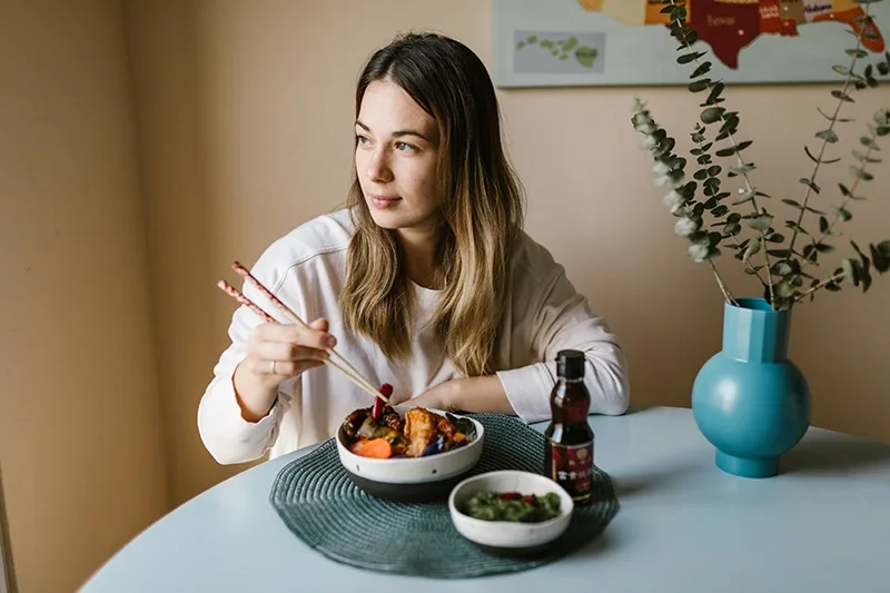 Frau isst chinesisches Essen mit Sojasauce