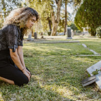 traurige Frau auf dem Friedhof