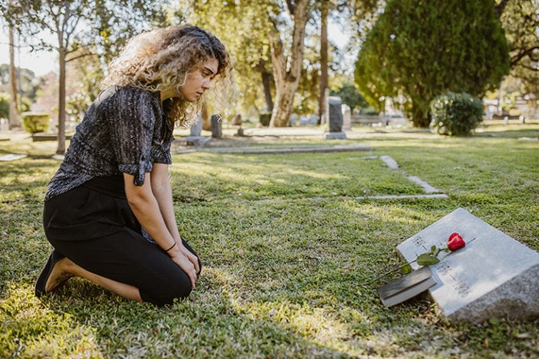 traurige Frau auf dem Friedhof
