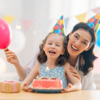 Tante und Tochter feiern Geburtstag mit Kuchen zu Hause