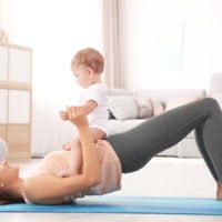 Junge Mutter macht Yoga mit Baby zu Hause