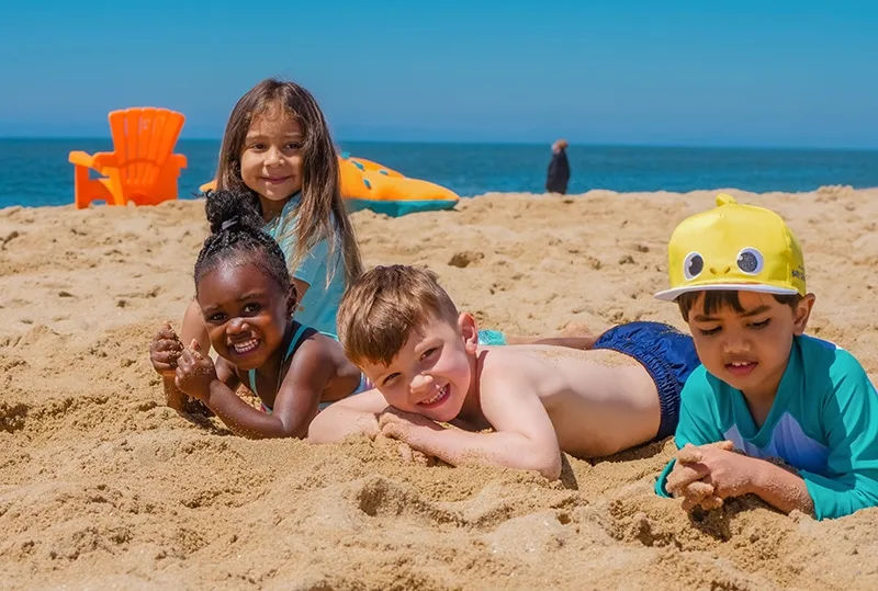 Gruppe von Kindern, die im Sand am Meer liegen