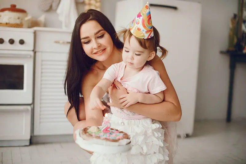Junge Frau hält eine Torte mit ihrer kleinen Nichte