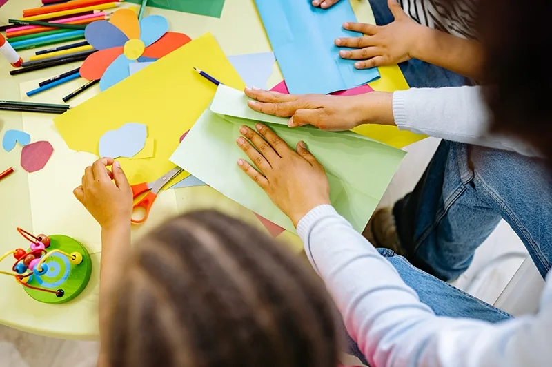 Kinder, die im Klassenzimmer Kunst mit farbigem Papier machen