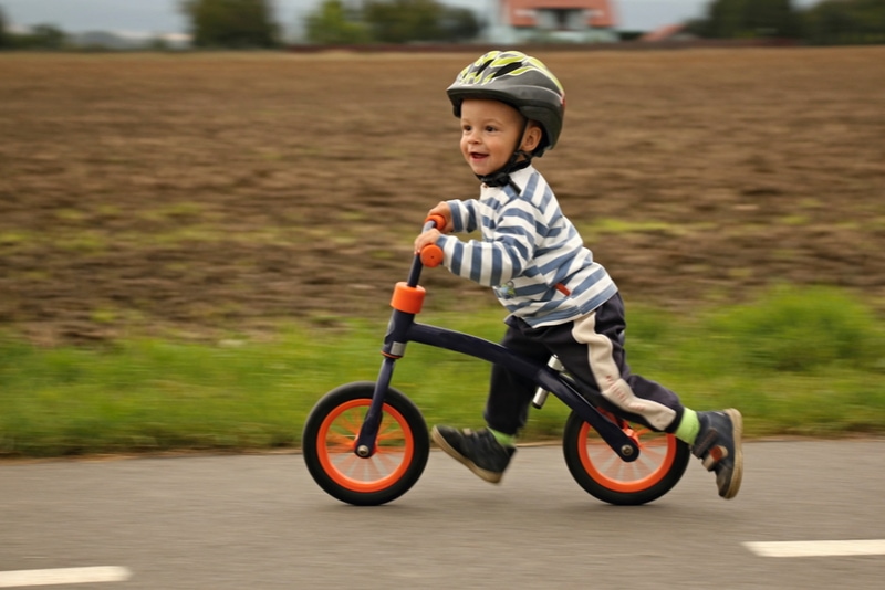 Kleiner Junge auf einem Laufrad