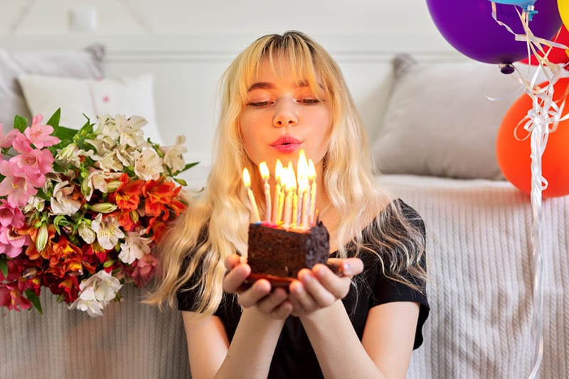 Mädchen mit Geburtstagskuchen mit brennenden Kerzen