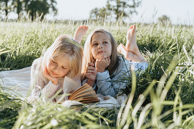 zwei kleine Mädchen lesen Buch auf einem Feld