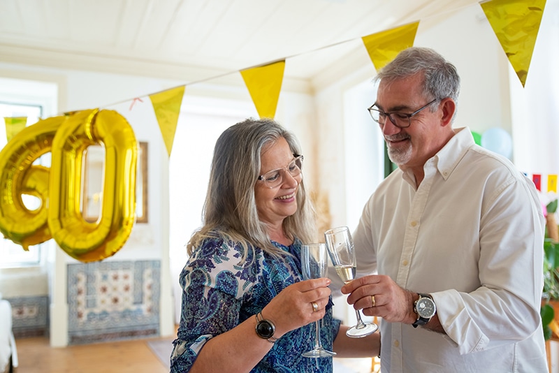 Mann und Frau stoßen bei der Feier zum 60. Geburtstag mit Champagner an