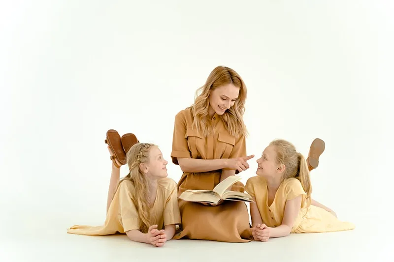 Mutter lacht mit ihren Töchtern, während sie ein Buch hält