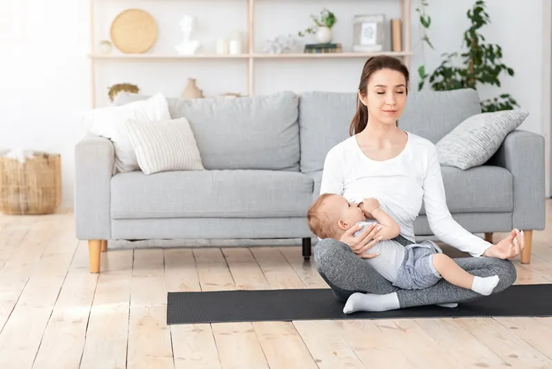 Mutter stillt Baby und meditiert zu Hause