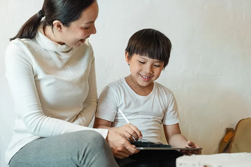 Mutter und Sohn lachen beim Benutzen des iPad