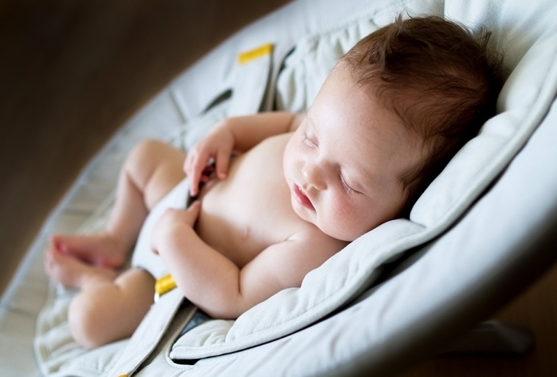 Neugeborenes Mädchen schläft in einer Schaukel im dunklen Raum
