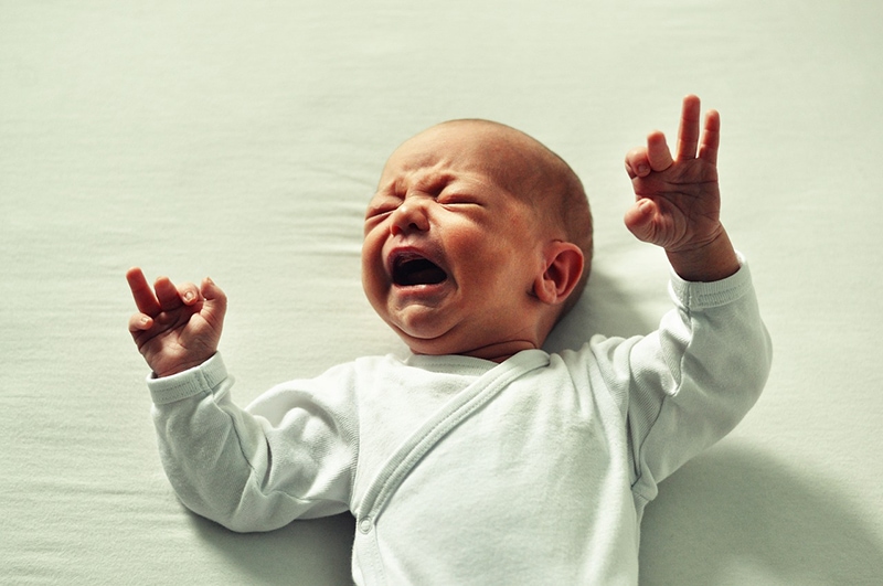Neugeborenes weint, während es auf dem Bett liegt