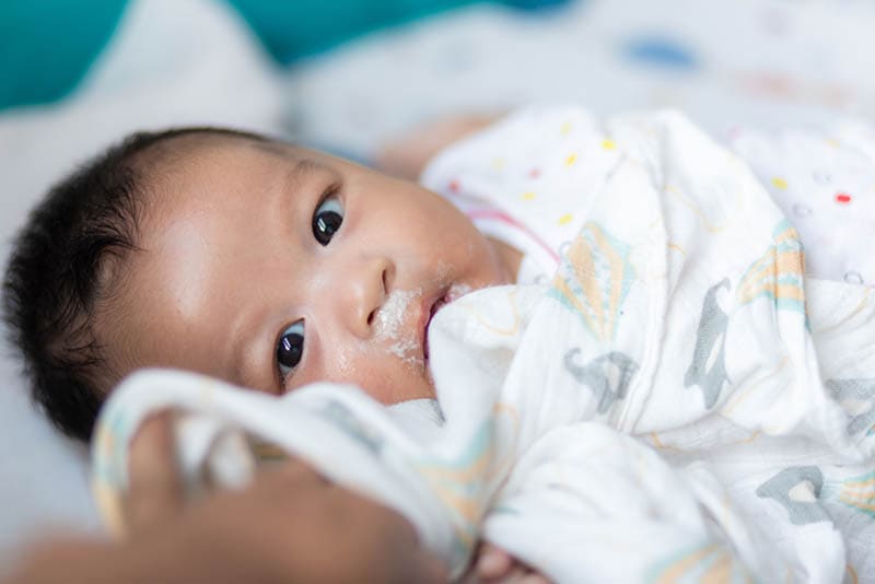 Säuglingsjunge erbricht nach dem Verzehr von Milch im Bett