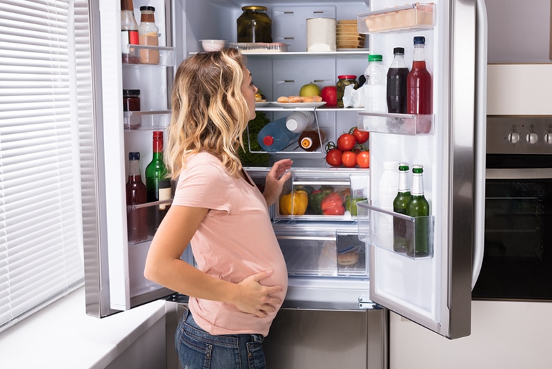 Schwangere Frau auf der Suche nach Essen im Kühlschrank