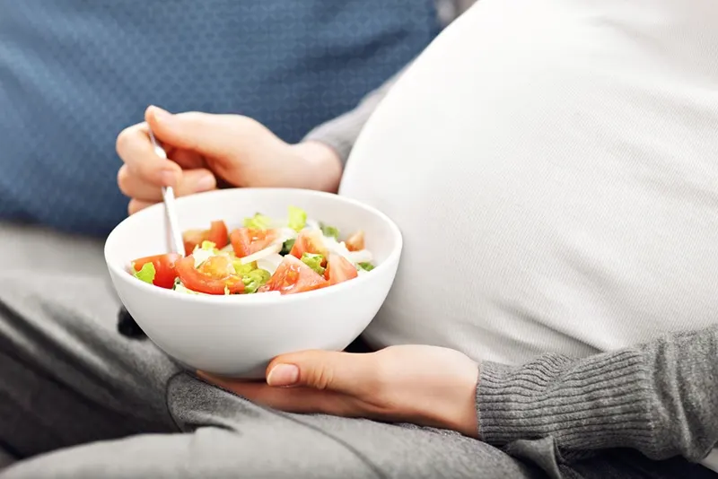 Schwangere, die zu Hause Salat isst
