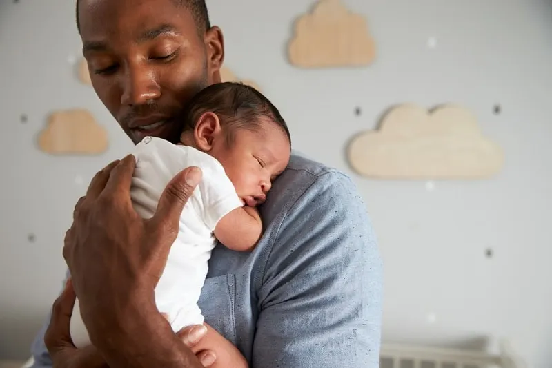 ein junger Vater hält sein Baby und versucht, es zum Einschlafen zu bringen