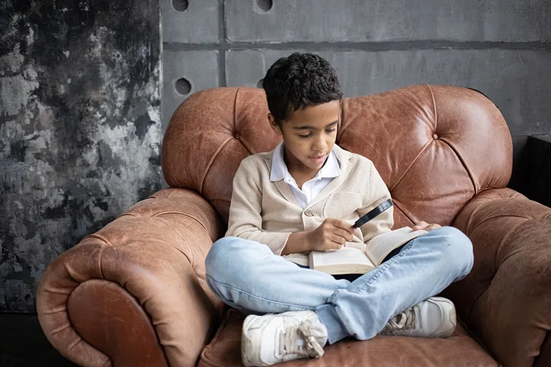 arabischer schüler mit einer lupe ein buch lesen